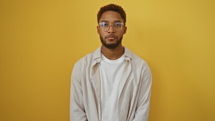 Fototapeta premium Handsome young man wearing glasses standing against isolated yellow background