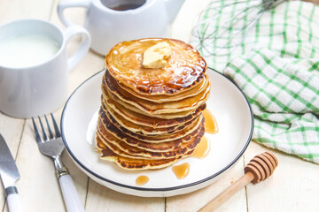 a dish of pancakes with honey and butter on the table as a breakfast menu