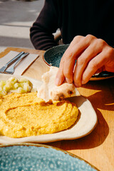 man dips a piece of naan bread on hummus