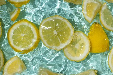 Refreshing turquoise citrus background with floating yellow lemon pieces