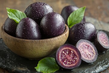 Exotic purple fruit in a bowl with slices showcasing vibrant interior and green leaves on wooden surface