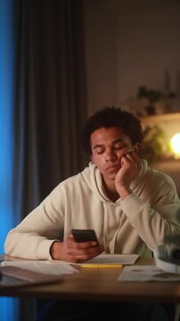 Vertical video of overjoyed young man reacting emotionally to an unexpected positive message at smartphone at home in the evening experiencing pure happiness and disbelief after reading great news