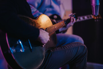 Two musicians engage in a passionate acoustic guitar performance, captured in a warmly lit studio...