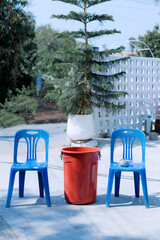 Blue plastic chairs and red plastic water buckets are placed outdoors.