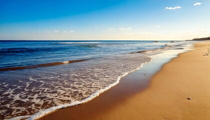 Fototapeta premium A shoreline with small waves lapping the sand. Soft beige, light blues, and natural textures