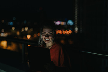 Young woman enjoying digital content on tablet at night city backdrop