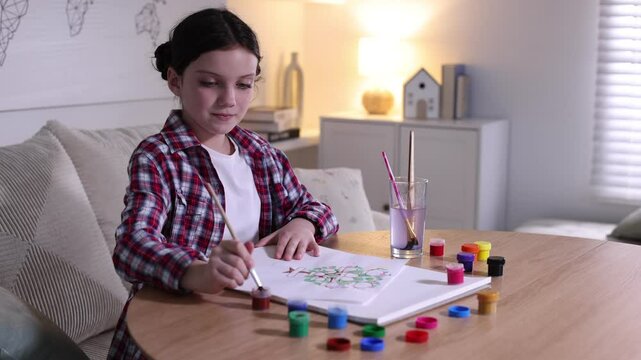 Girl drawing her family tree at wooden table indoors