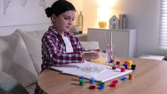Girl drawing her family tree at wooden table indoors