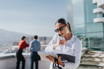 A group of business people stands on a high-rise balcony, engaged in discussion and strategizing future plans. A woman in the foreground speaks on the phone and takes notes.