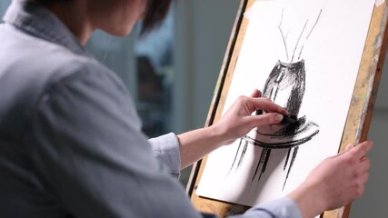 Woman drawing picture on easel in studio, closeup