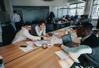 Business employees engage in discussion and strategy planning around a table in a modern office...
