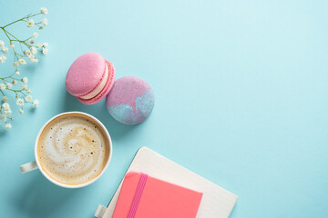 Cup of coffee, macaroon and flower on blue background.