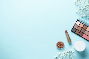 Make up products on blue with flowers.