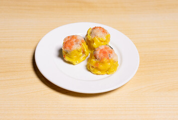 Dimsum on white plate isolated on wooden background. After edits.