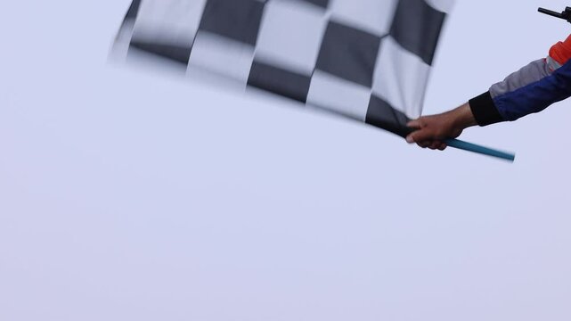 Man holding and waving checkered race flag on finish podium, Finish line and checkered flag, Race flag at the finish line on a race track, Victory achievement success motorsport.