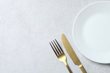 White empty plate with cutlery on a gray background