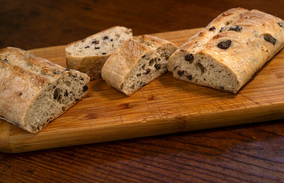 Sliced olive ciabatta bread on wooden cutting board