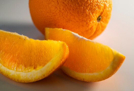 Close-up of two slices of orange next to whole orange on white background