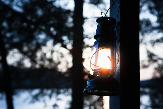 Kerosene lantern hanging by lakeside camp at sunset