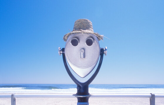 Coin-operated binoculars in straw hat on beach