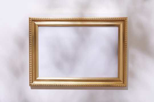 Empty golden picture frame on white wall