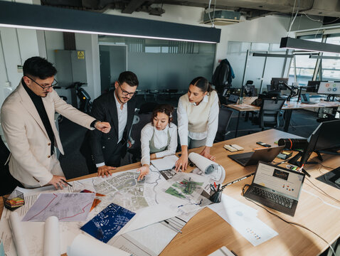 A group of people, including a project leader with crutches, collaborate on project plans in a contemporary office setting, analyzing maps and documents. The atmosphere is focused and cooperative.
