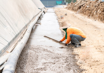 The worker is troweling the plaster to make it smooth.
