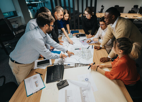 A multicultural group of business people engaging in a collaborative brainstorming session. They are discussing ideas and strategies, analyzing proposals, and planning for successful project outcomes.