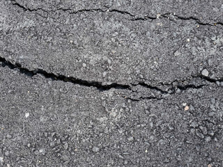 Obraz premium Cracked asphalt road surface background. Surface texture of new asphalt road with cracks. Alligator type cracking in the asphalt pavement. Cracks on asphalt in a afternoon day.