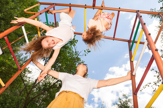 Happy kids playing on monkey bars with mom on a sunny day