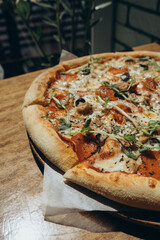  Freshly baked pepperoni pizza with herbs served at cozy restaurant