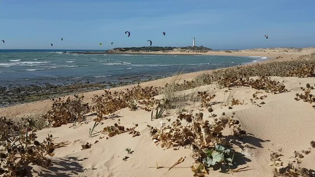 Kitesurfers glide over the waves enjoying on a windy day at the Canos de Meca, a wild, scenic beach along Vejer de la Frontera's coast in Cadiz, Andalusia, Spain.