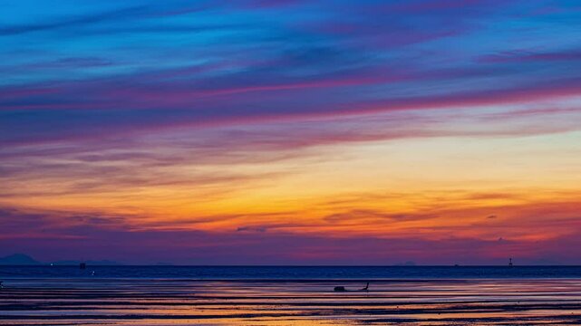 Time lapse amazing sky at twilight over the shallow sea.
Villagers go out to collect shellfish during low tide. 
A striking seascape capturing the vivid hues of sky blending colors over the ocean