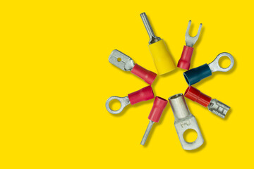 Various types of wire terminals on a bright yellow background arranged in a circular pattern