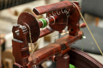 Distaff Day Traditional wooden spinning wheel with green yarn in workshop