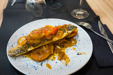 Grilled sea bass with vegetables and sauce garnished on white plate