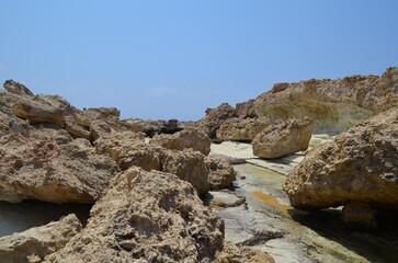 Rocky coastal landscape with eroded limestone formations under clear blue sky