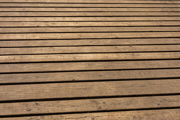 Obraz premium view of a brown wooden deck or platform filled with a repeating pattern of parallel wooden planks with knots, grains, and weathered imperfections. Natural materials, construction, outdoor settings