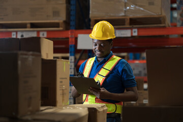 Warehouse worker, African American male warehouse worker. Male worker holding clipboard checking barcodes on product packaging boxes on shelf pallet at storage warehouse