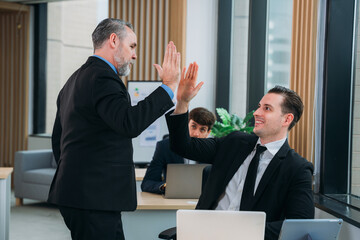A group of different business people are sitting around a big meeting table in a modern office.