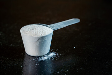 White powder in a scoop on a dark surface close-up