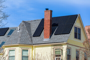 Classic yellow home with red brick chimney and solar panels in Brighton, Massachusetts, USA
