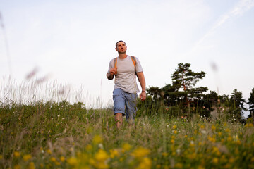A male tourist is walking across the field.