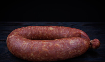 Krakow sausage on a dark background. Circle of smoked sausage.