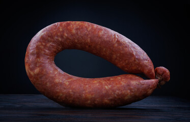 Krakow sausage on a dark background. Circle of smoked sausage.