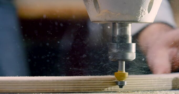 Furniture manufacturing. Detail processing close-up. The master's hands work with a furniture detail on a milling machine. A master crafts furniture detail on a milling machine.