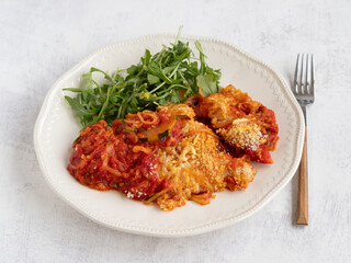 Plate of courgette spaghetti with tomato sauce and cheese au gratin served with rocket salad