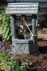 A tiny well with water coming from a bucket