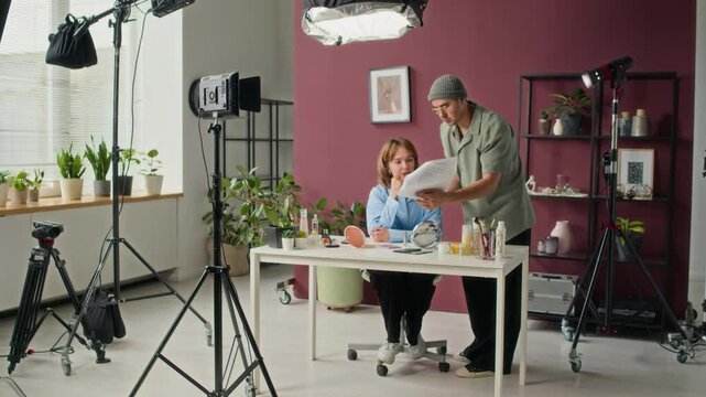 Film director discussing script with actress, preparing for video recording in professional studio with