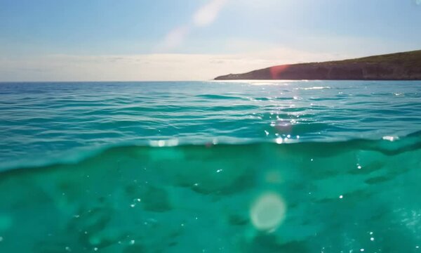 Sea water surface. Low angle view over clear azure sea water. Sun glare. Abstract nautical summer ocean nature. Holiday, vacation and travel concept. Nobody. Slow motion. Weather and climate change